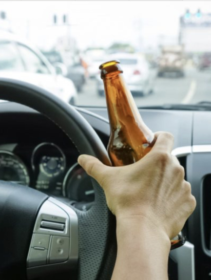 Motorist holding a bottle of alcohol while driving under the influence on Blackout Wednesday.